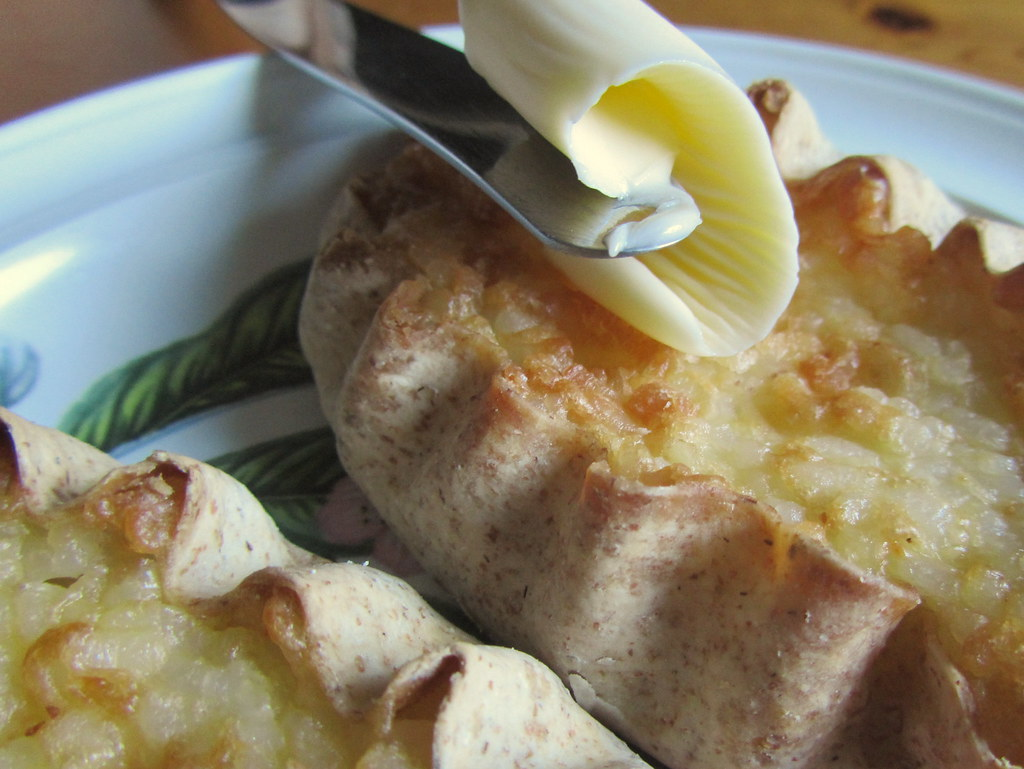 An image of two karjalanpiirakka served with butter.