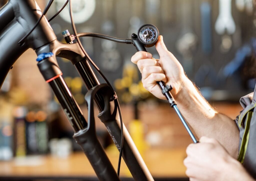 Repairman pumping shock absorber of the mountain bike in the workshop.