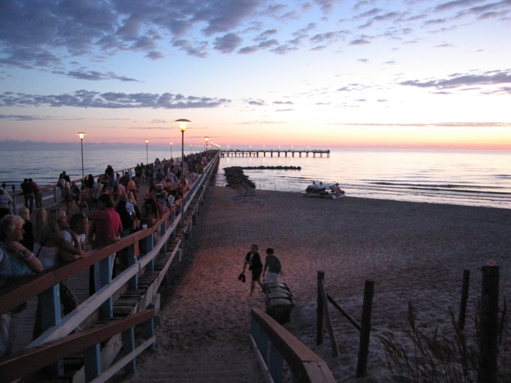 An image of tourists enjoying the sunset in a Palanga seafront.