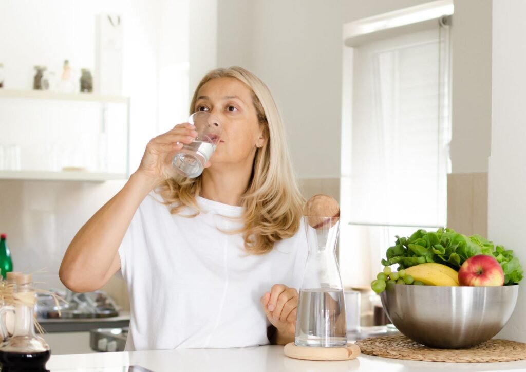 A woman drinking water to stay hydrated.
