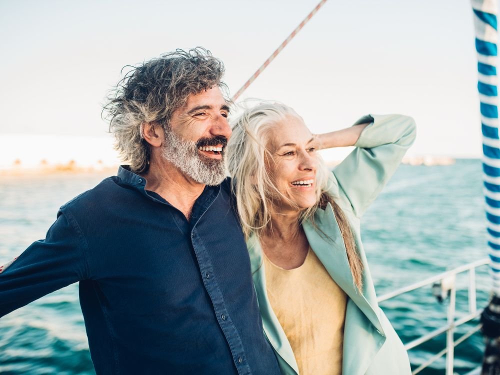 An image of two senior couple enjoying the sea breeze during their cruise retirement trip. 