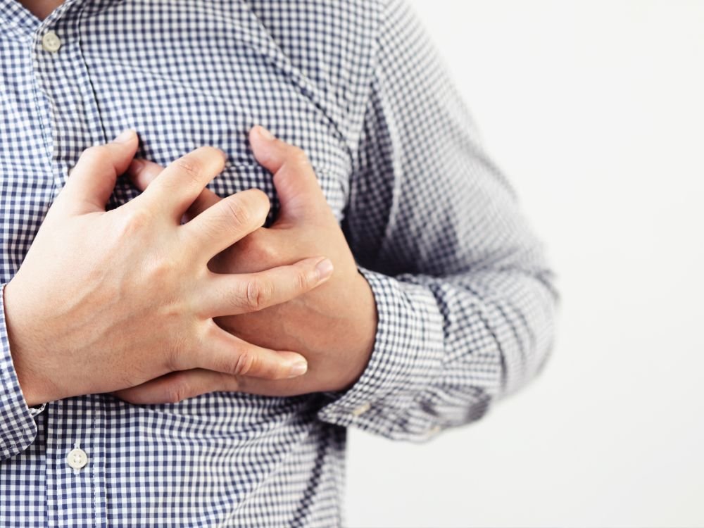 An image of a man holding his chest.
